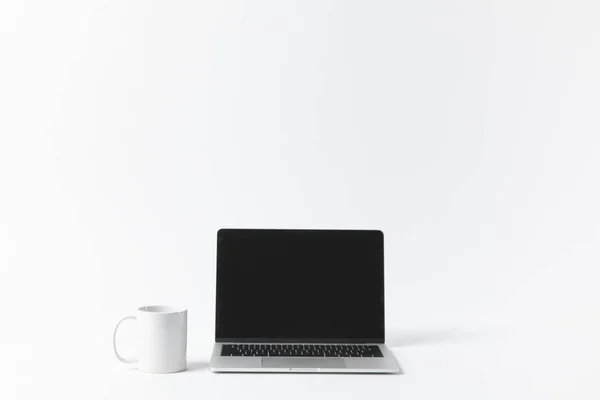 Close up view of laptop with blank screen and white mug isolated on white — Stock Photo