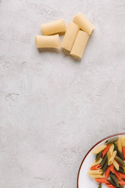 Vue de dessus de deux types de pâtes crues sur table en béton — Photo de stock