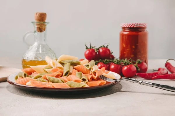 Colorful pasta on plate with various food on background on concrete surface — Stock Photo