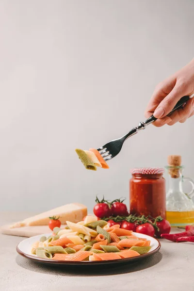 Cropped shot of woman eating delicious pasta with fork on concrete tabletop — Stock Photo