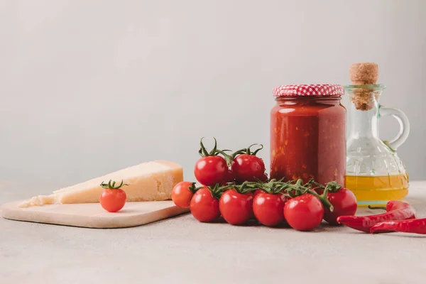 Pomodorini con formaggio, ketchup e olio d'oliva su tavolo di cemento, ingredienti della cucina italiana — Foto stock