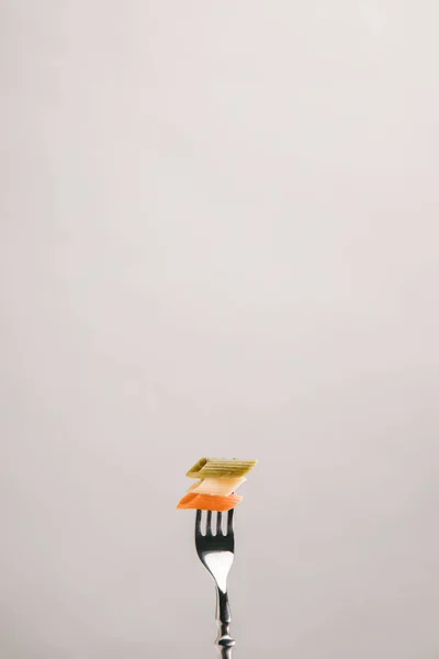 Macarrão colorido perfurado com garfo isolado em cinza — Fotografia de Stock