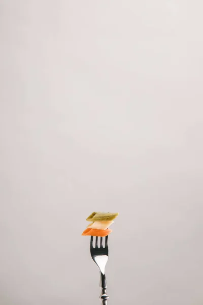 Colored pasta pierced with fork isolated on grey — Stock Photo