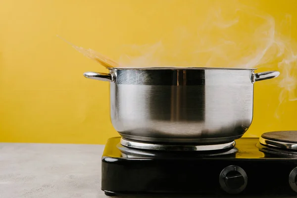 Close-up shot of spaghetti boiling in stewpot on yellow — Stock Photo