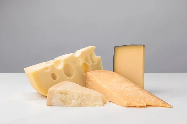 Vista de primer plano de los diferentes tipos de queso en gris - foto de stock