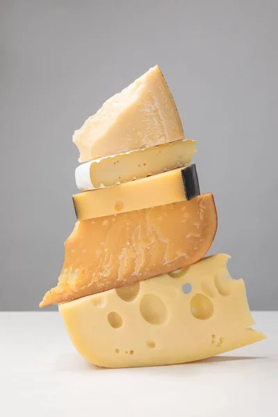 Vista de cerca de la pila de diferentes tipos de queso en gris - foto de stock