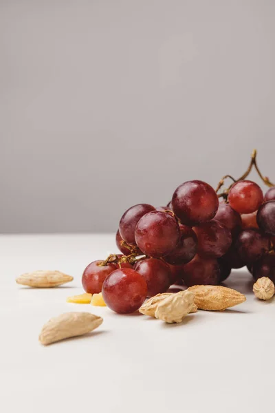 Vue rapprochée des raisins et des amandes sur gris — Photo de stock