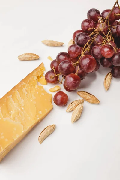 Closeup shot of parmesan cheese, almond and grapes on white — Stock Photo