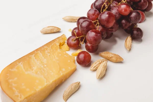 Closeup shot of parmesan cheese, almond and grapes on white — Stock Photo