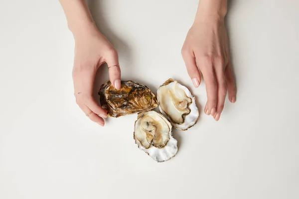 Mãos femininas com ostras frescas na mesa branca — Fotografia de Stock