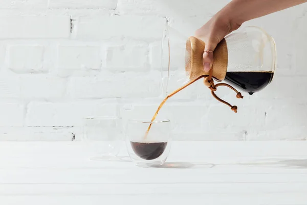 Cropped shot of woman pouring alternative coffee from chemex into glass mug — Stock Photo