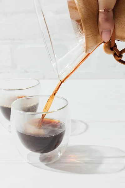 Cropped image of woman pouring alternative coffee from chemex into glass mug — Stock Photo