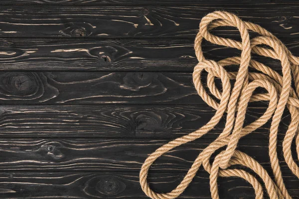 Top view of brown nautical rope on dark wooden surface — Stock Photo