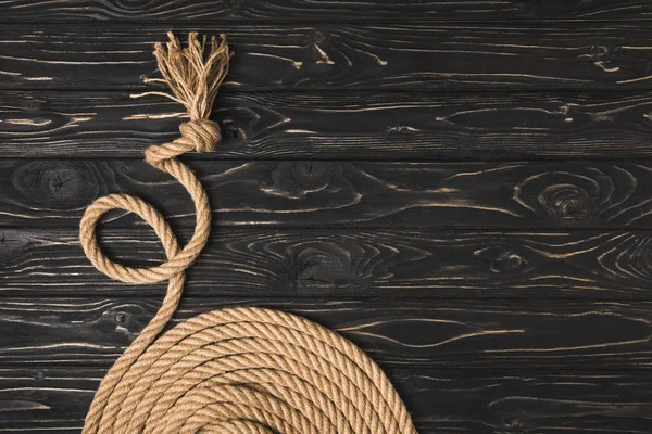 Vue partielle de la corde nautique nouée brune disposée en cercle sur une surface en bois — Photo de stock