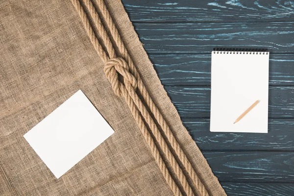 Vista superior de papel vacío sobre tela de saco con cuerda anudada y libro de texto en blanco con lápiz - foto de stock