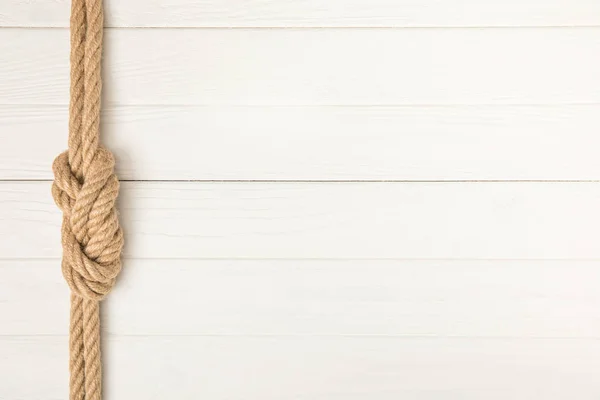 Top view of brown nautical rope with knot on white wooden surface — Stock Photo