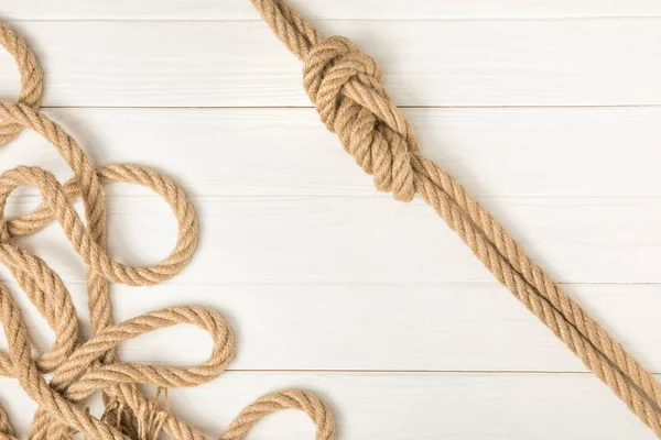 Top view of brown nautical knotted ropes on white wooden planks — Stock Photo