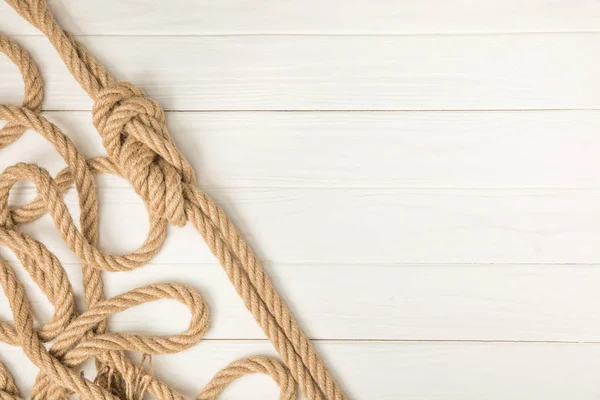 Vue de dessus de corde noeud nautique marron sur planches de bois blanc — Photo de stock