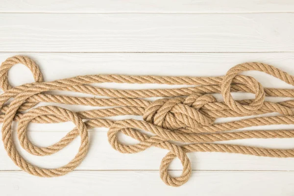 Top view of brown nautical knotted ropes on white wooden surface — Stock Photo