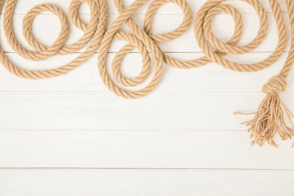Top view of brown nautical knotted rope on white wooden background — Stock Photo