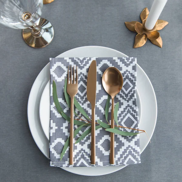 Flache Liege mit altmodischem Besteck, Serviette, grüner Pflanze auf Tellern auf Tischplatte — Stockfoto