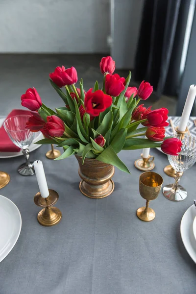 Close up view of bouquet of red tulips on tabletop with arranged vintage cutlery and candles — Stock Photo