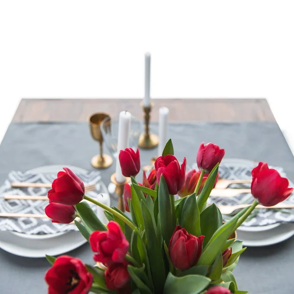 Selektiver Fokus von Strauß roter Tulpen und rustikaler Tischdekoration dahinter — Stockfoto