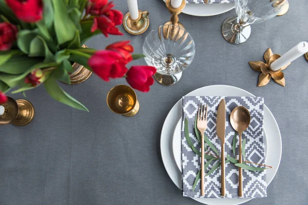 Vue du dessus de la table rustique avec bouquet de tulipes rouges et argenterie à l'ancienne — Photo de stock