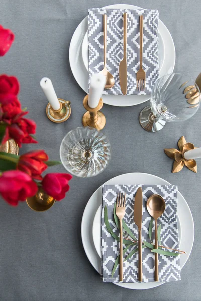 Top view of rustic table setting with bouquet of red tulips and arranged old fashioned silverware — Stock Photo