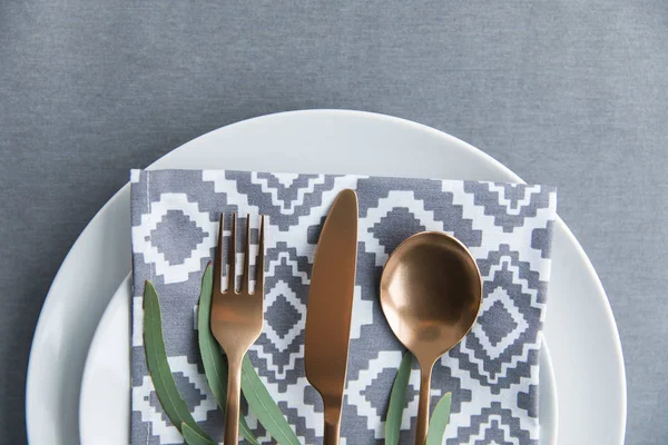 Flat lay with rustic table setting with vintage tarnished silverware, napkin, green plant and plate — Stock Photo