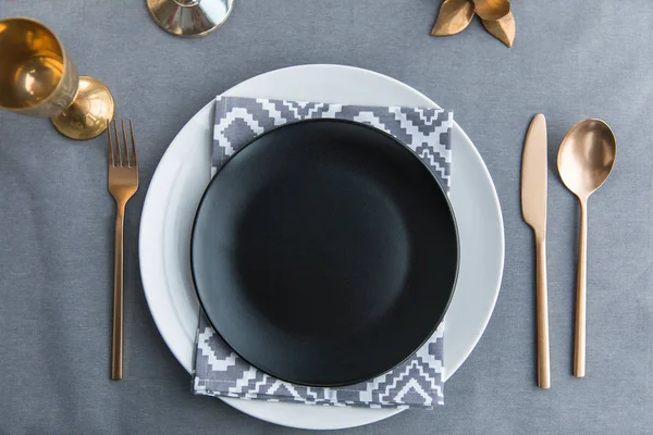 Vista superior de plato vacío negro, servilleta y cubiertos empañados a la antigua en la mesa - foto de stock