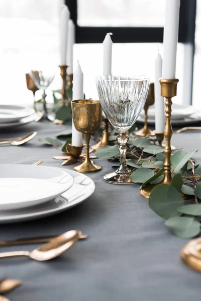 Nahaufnahme der rustikalen Tischdekoration mit Eukalyptus, Vintage-Besteck, Kerzen im Kerzenständer und leeren Tellern — Stockfoto