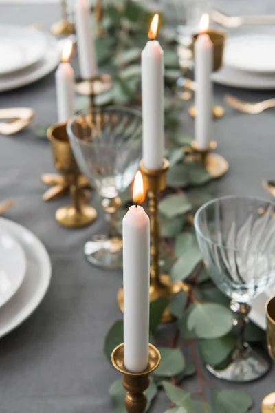 Mise au point sélective de table rustique avec eucalyptus, couverts à l'ancienne, bougies dans des bougeoirs et assiettes vides — Photo de stock