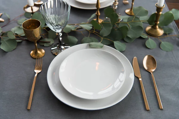 Vue rapprochée de la disposition rustique de la table avec eucalyptus, couverts vintage et assiettes vides — Photo de stock