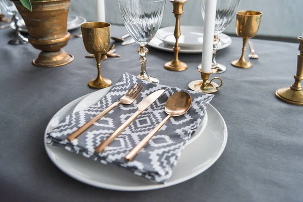 Close up view of rustic table setting with old fashioned cutlery and napkin on plates, candles and empty wine glasses on surface — Stock Photo