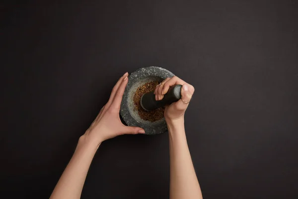 Partial view of woman with mortar and pestle on black surface — Stock Photo