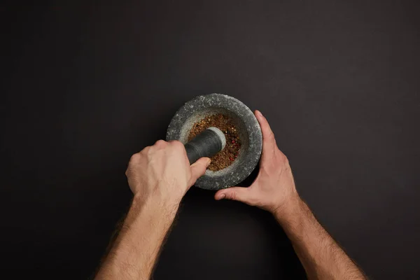 Partial view of man with mortar and pestle on black surface — Stock Photo