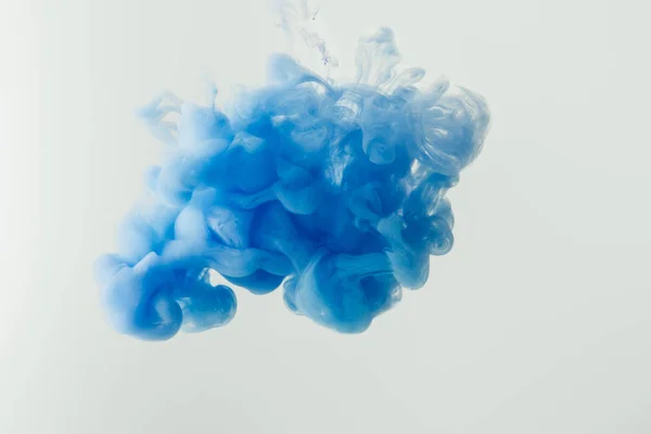 Primer plano de salpicadura de tinta azul brillante en agua aislada en gris — Stock Photo