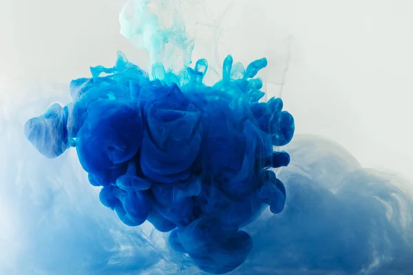 Nahaufnahme des Mischens von blauen und türkisfarbenen Farbspritzern im Wasser isoliert auf grau — Stockfoto