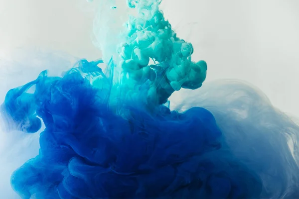 Nahaufnahme der Mischung von blauen und türkisfarbenen Tinten spritzt im Wasser isoliert auf grau — Stockfoto