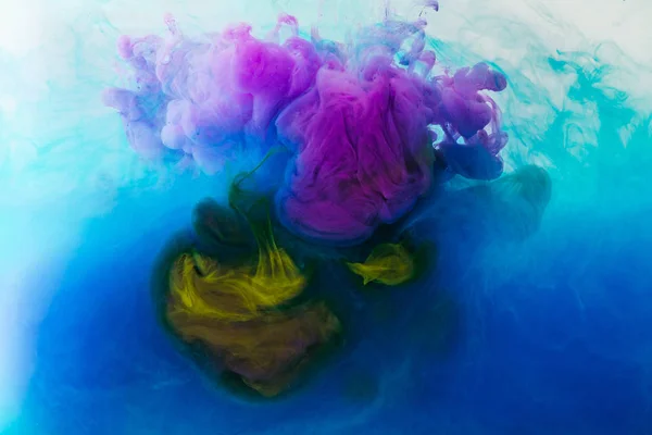 Full frame image of mixing of blue, turquoise, yellow and purple inks splashes in water — Stock Photo