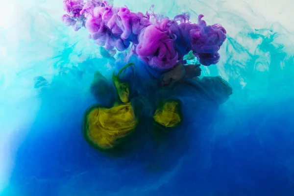 Full frame image of mixing of blue, turquoise, yellow and purple paints splashes  in water — Stock Photo