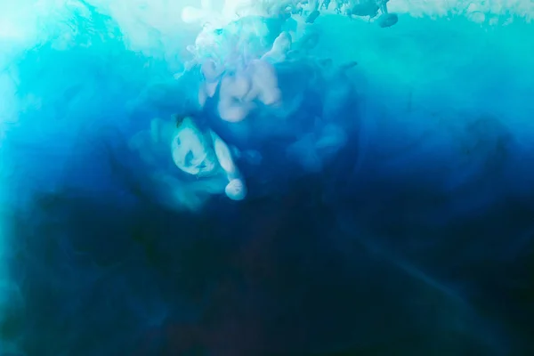 Immagine full frame di miscelazione di blu, turchese, bianco e nero spruzzi di vernici in acqua — Foto stock
