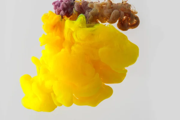 Vista de perto de mistura de tintas amarelas e roxas salpicos em água isolada em cinza — Fotografia de Stock