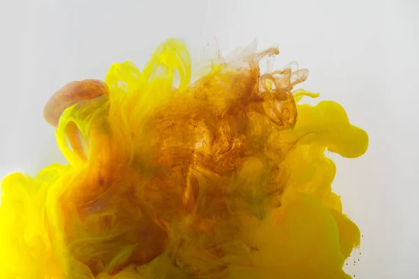 Close up view of mixing of yellow and brown ink splashes in water isolated on gray — Stock Photo