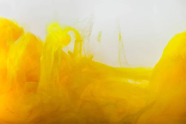 Close up view of mixing of yellow and brown paints splashes in water isolated on gray — Stock Photo