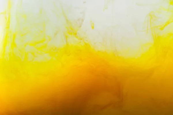 Близкий обзор фона с перемешиванием брызг желтых и коричневых красок в воде — стоковое фото