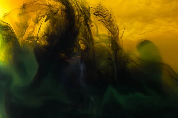 Immagine full frame di miscelazione di vernici gialle, verdi e nere schizzi in acqua — Foto stock