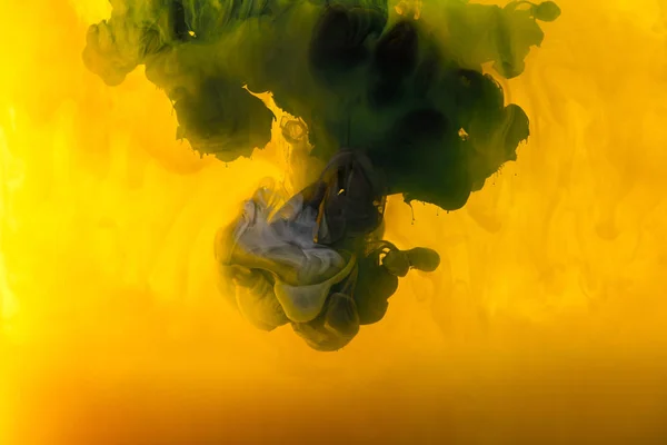 Imagen de marco completo de mezcla de pinturas amarillas, verdes y negras salpicaduras en el agua — Stock Photo