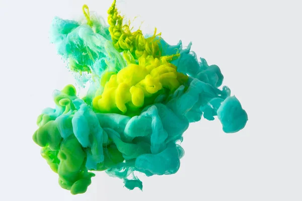 Close up view of mixing of green, yellow and bright turquoise inks splashes in water isolated on gray — Stock Photo